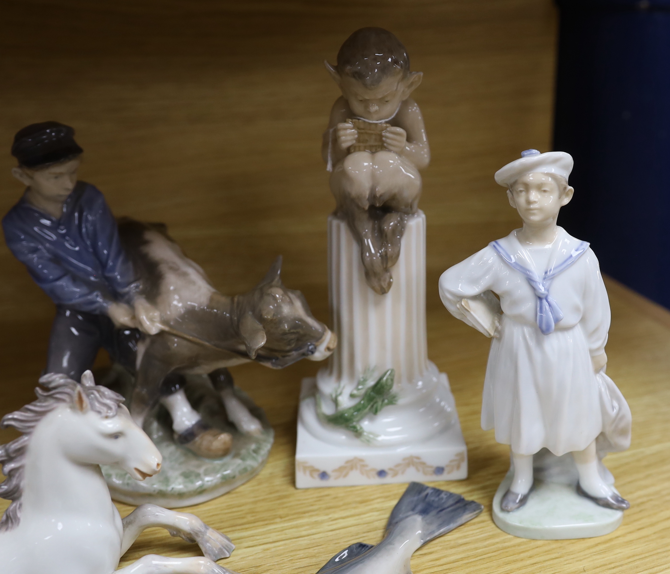 Seven mixed Royal Copenhagen models including children, fish, a fawn, a sailor, a cow and a seahorse (hippocampus), the largest 23cm high